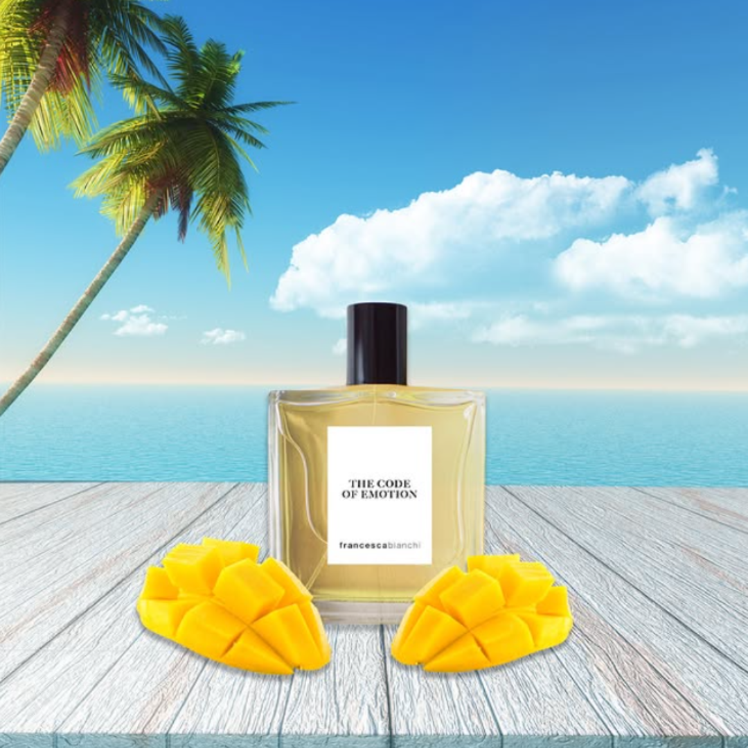 Perfume bottle labeled 'The Code of Emotion' with mango slices on a tropical setting background