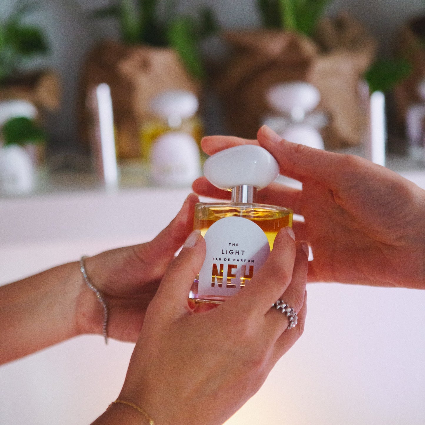 Person holding a bottle of perfume with a blurred indoor setting