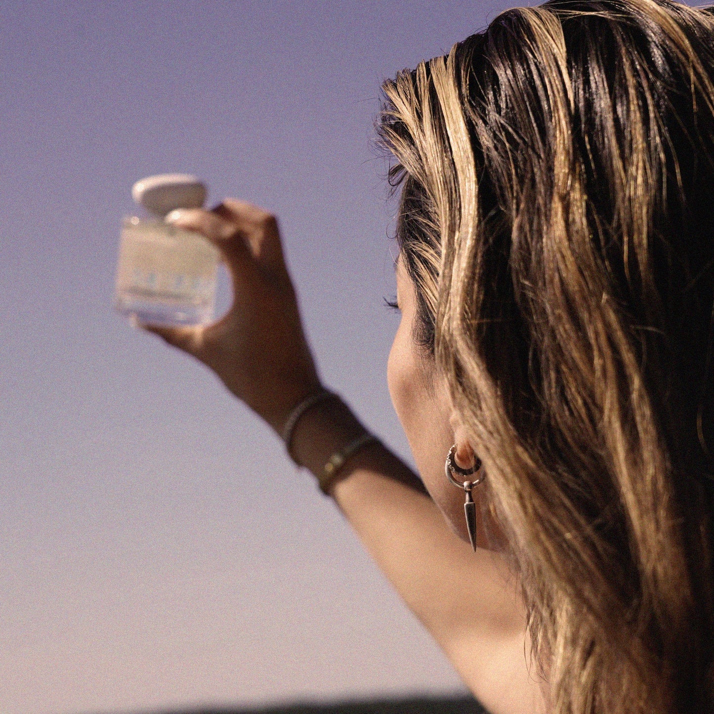 Woman holding a small container against a sunset sky