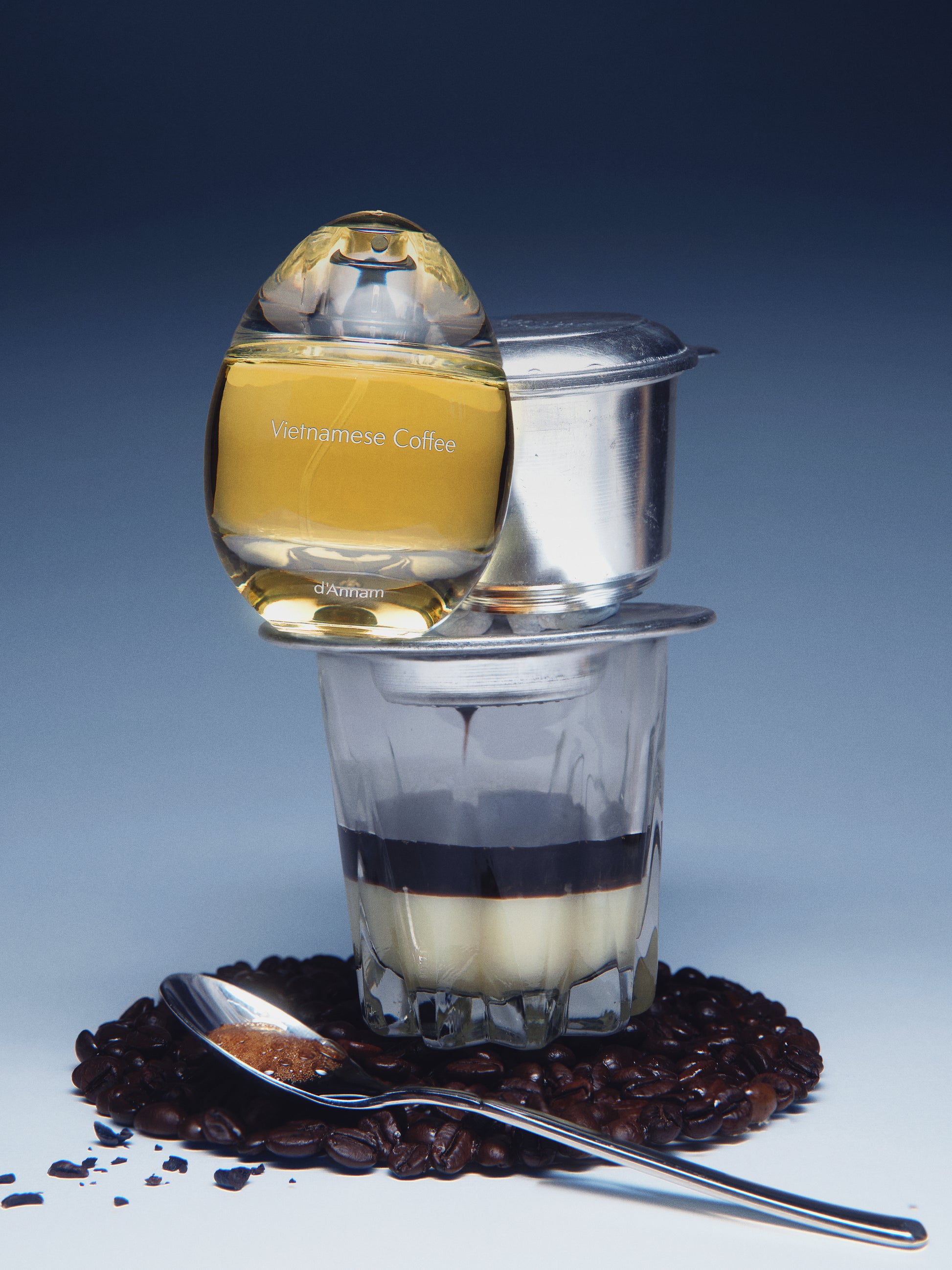 Bottle of coffee liqueur, glass with layered drink, and coffee beans on a blue background