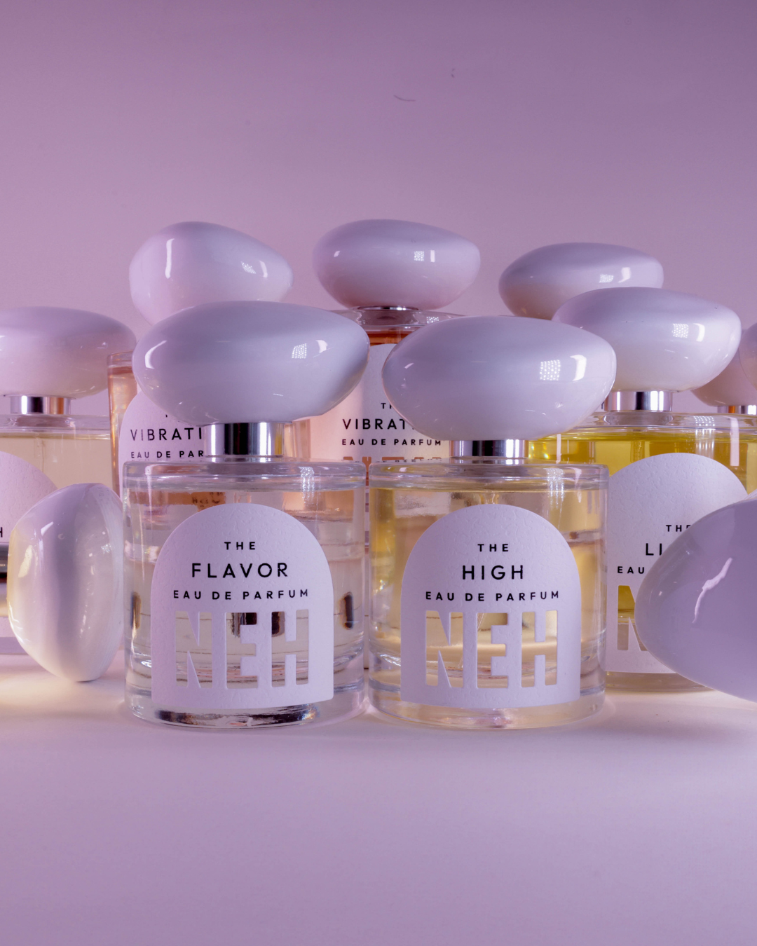 Collection of perfume bottles with visible labels on a light pink background