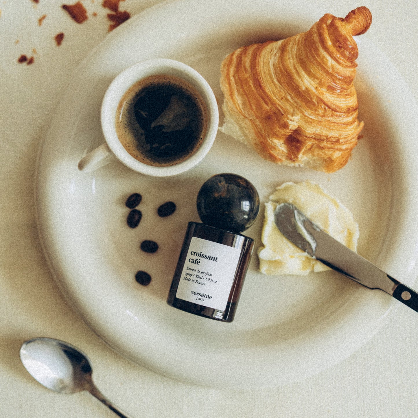Café au lait with croissant, coffee, and a bottle of La Colombe coffee on a white plate.