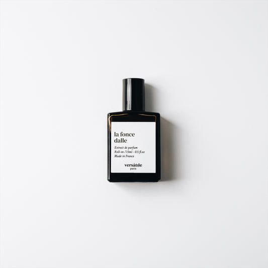 Perfume bottle with black cap and white label on a light gray background