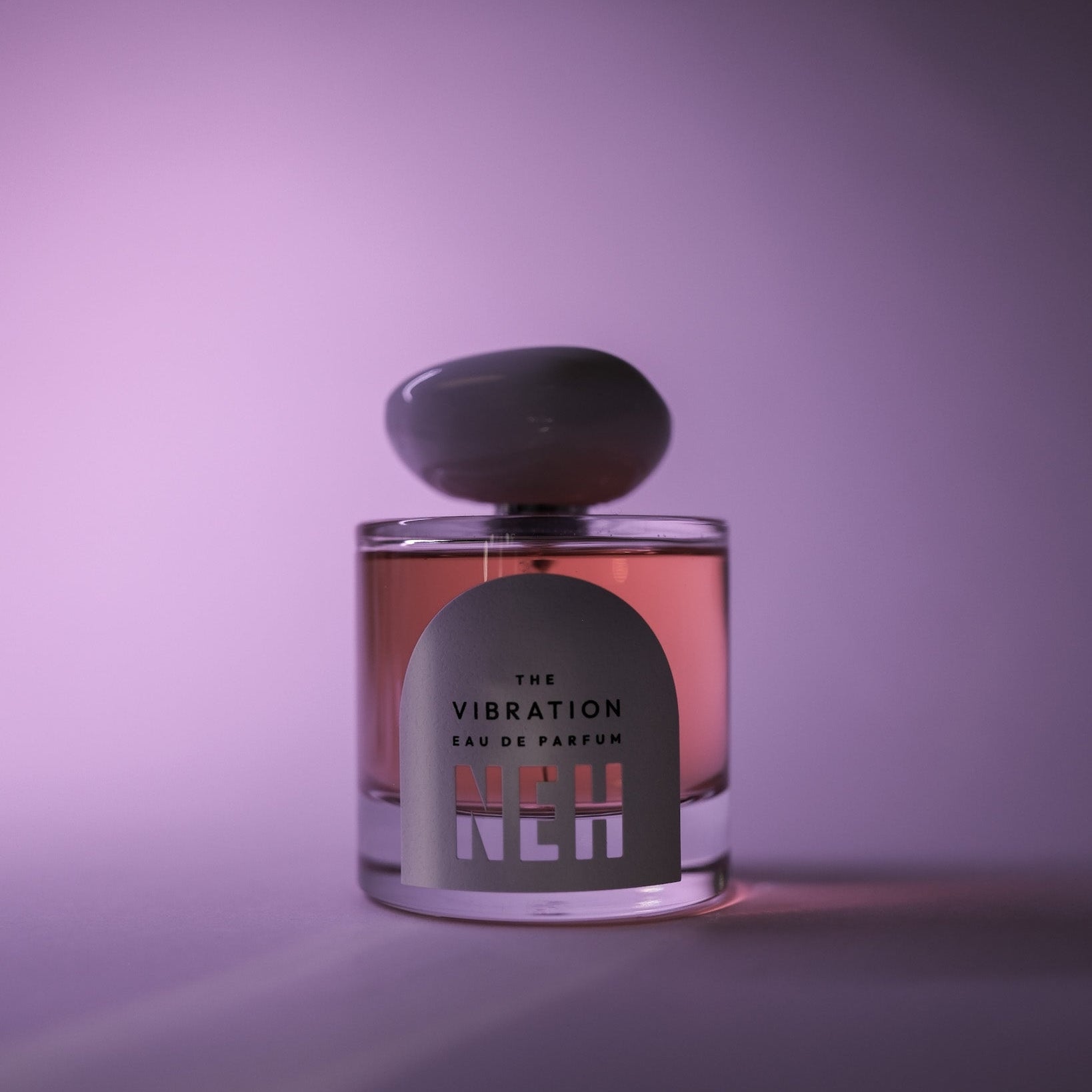 Perfume bottle labeled 'The Vibration' on a purple background