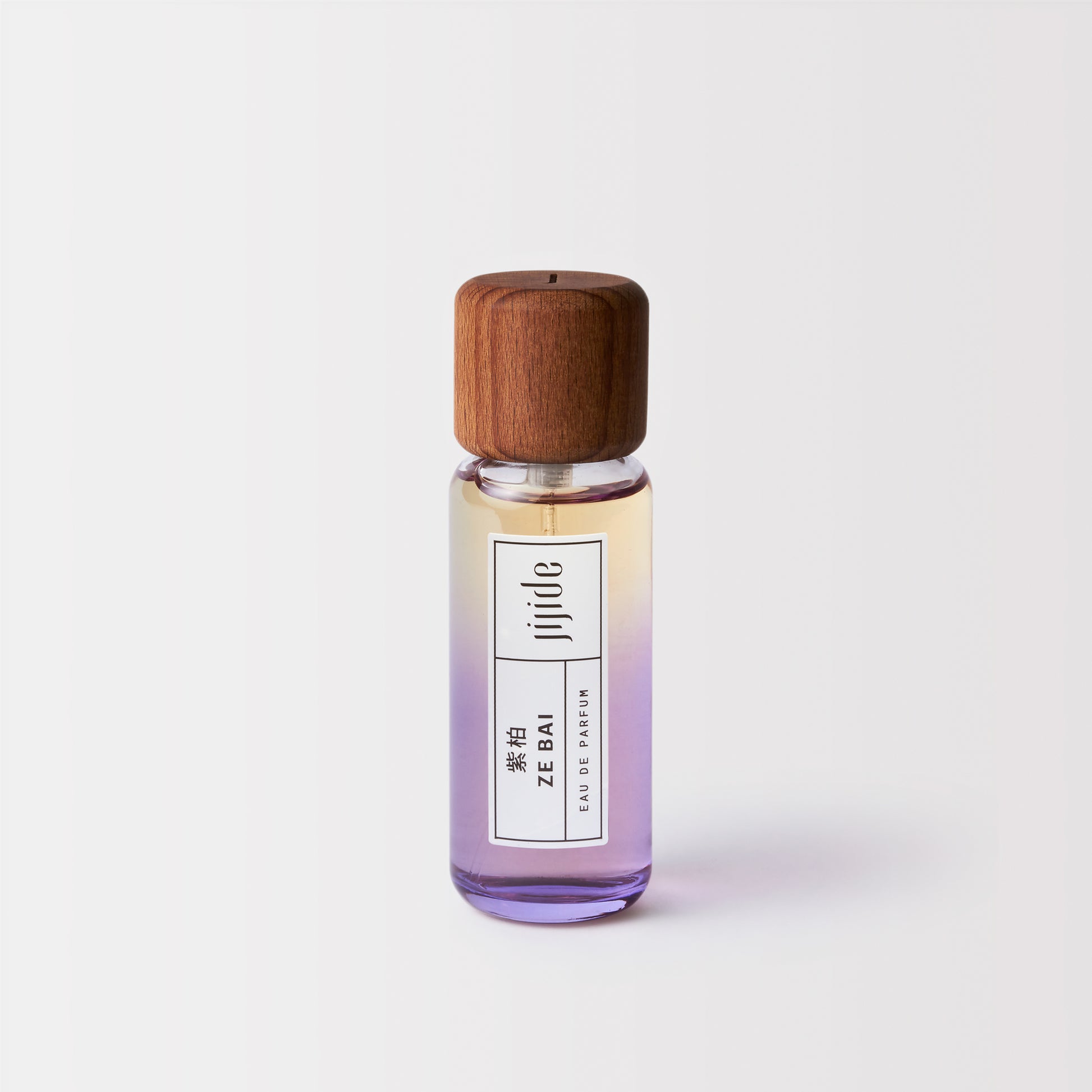 Small perfume bottle with wooden cap on a light gray background