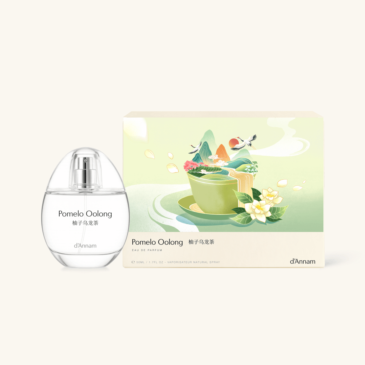 A clear glass bottle of d'Annam Pomelo Oolong tea with a silver cap stands next to its illustrated product box on a light cream background.