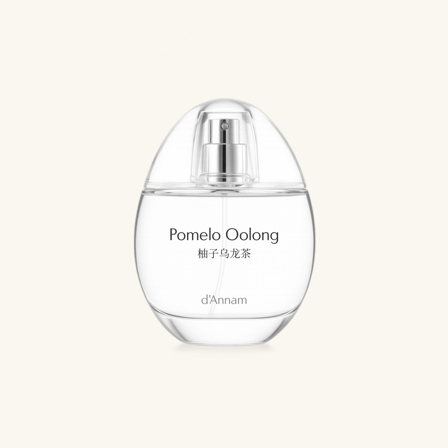 A clear glass perfume bottle with a silver spray nozzle, labeled 'Pomelo Oolong' and 'd'Annam', centered on a light cream background.