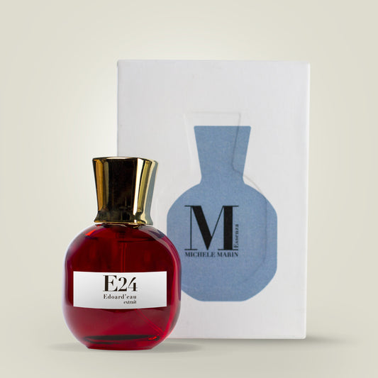 Red perfume bottle with gold cap and white label next to a blue and white box on a beige background