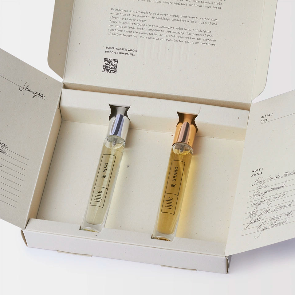 Two small bottles with labels inside an open box on a white background