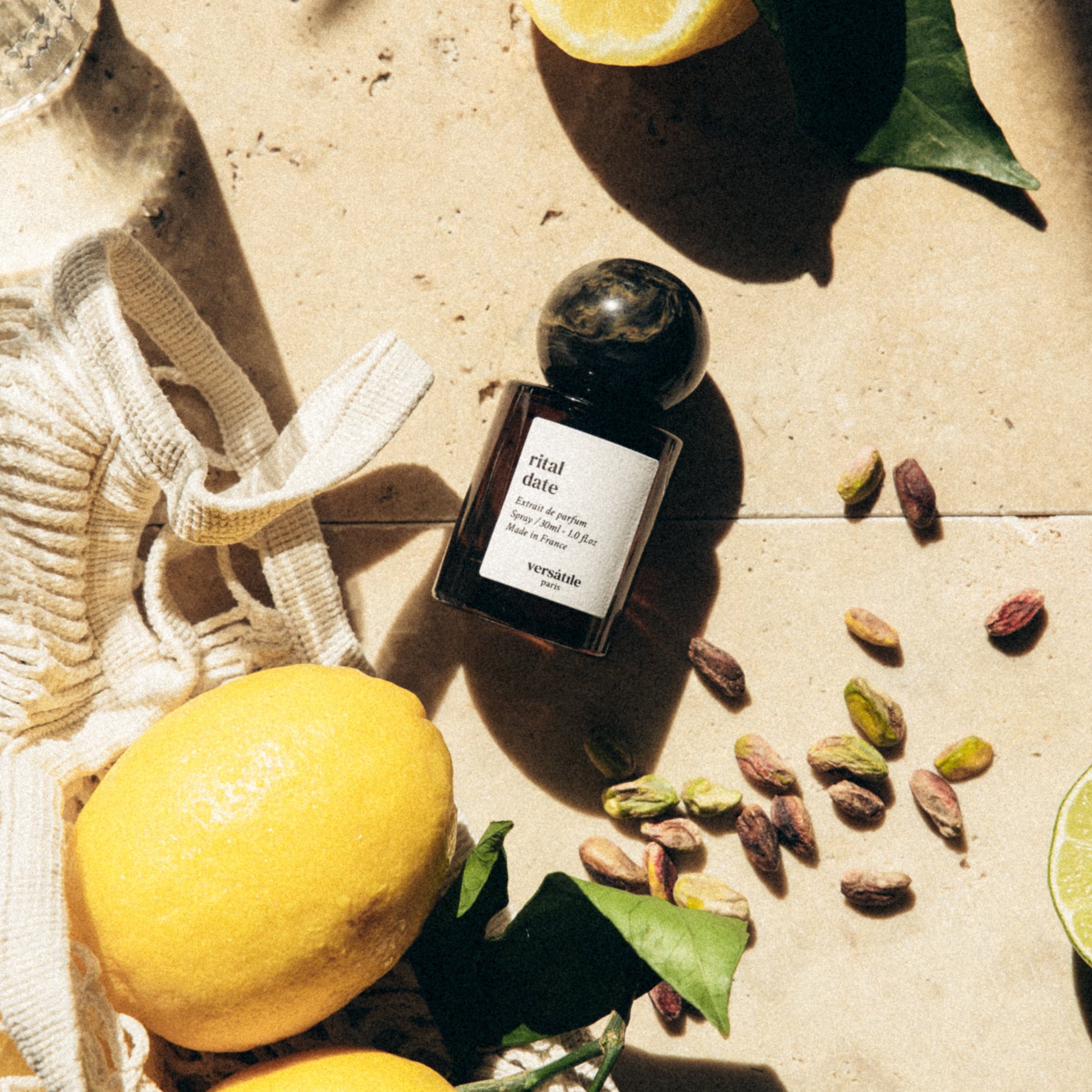 Perfume bottle with lemons and seeds on a textured surface